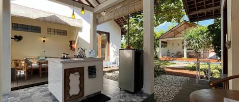 A covered outdoor area with a kitchen counter, dining table, and chairs.