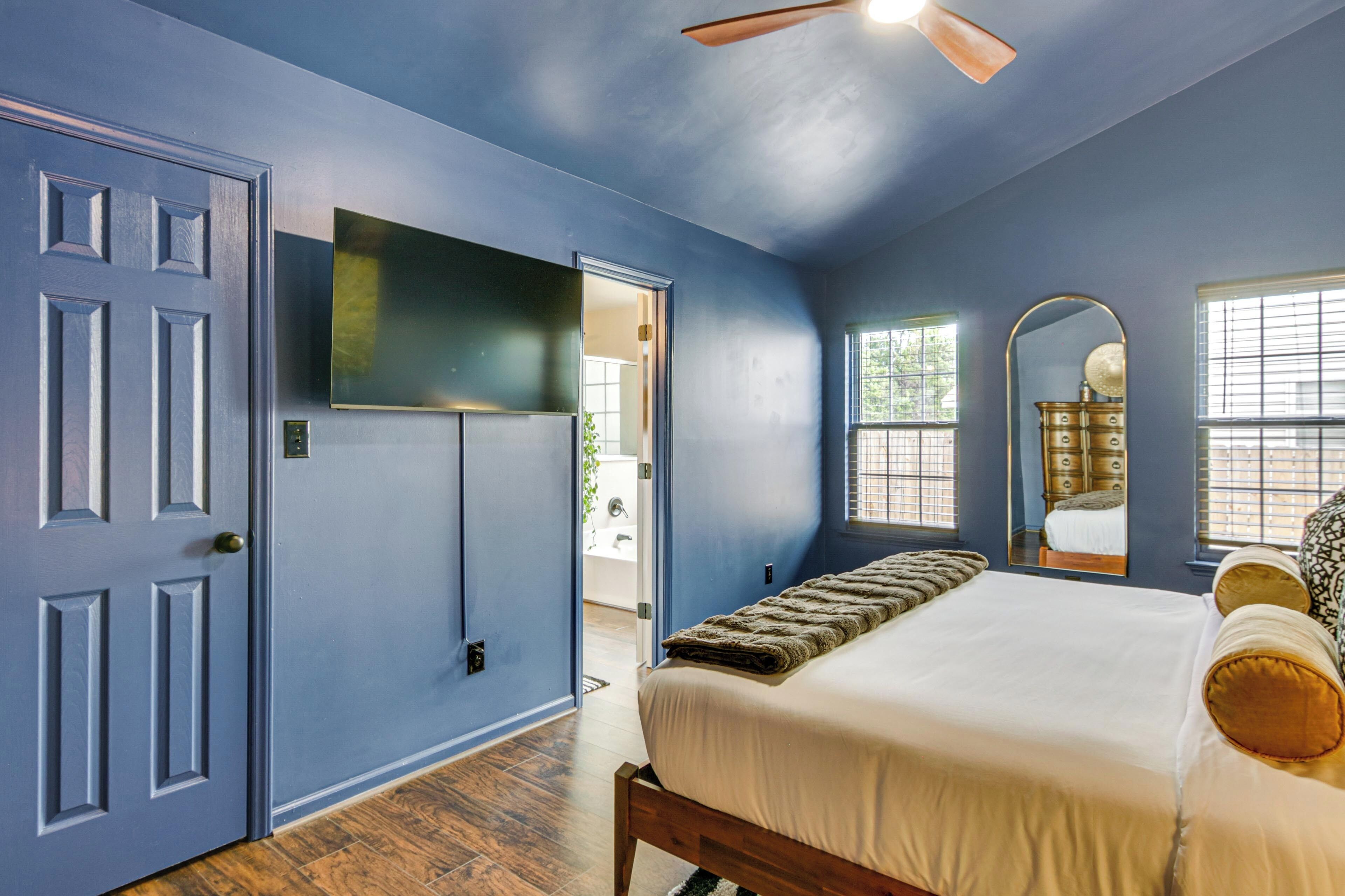 Un dormitorio con cama, televisión, puerta y ventana.