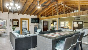 A spacious patio with a large wicker dining table and chairs, a ceiling fan, and a television mounted on the wall. - Private Pool & Dock: Riverfront 'Bridge Escape' (North Fort Myers)