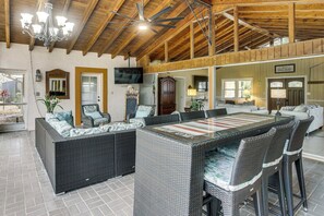 A spacious patio with a large wicker dining table and chairs, a ceiling fan, and a television mounted on the wall. - Private Pool & Dock: Riverfront 'Bridge Escape' (North Fort Myers)
