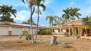 A residential property with a paved courtyard, palm trees, and a garage. - Private Pool & Dock: Riverfront 'Bridge Escape' (North Fort Myers)