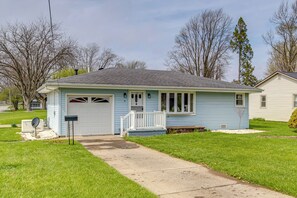 Une maison de plain-pied avec un garage, un porche à l’avant et une pelouse.