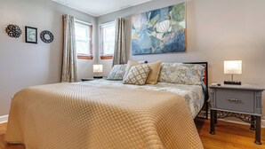 A bedroom with a large bed, two bedside tables, a nightstand, a painting, and two windows with curtains. - 7 Mi to Mississinewa Lake! Charming Home (Converse)
