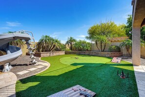 Un patio trasero con césped artificial, una antena parabólica y una zona de terraza.
