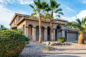 A two-story house with a tiled roof, arched columns, and a gravel driveway. - Swim-Up Bar & Games! Ultimate Goodyear Group Stay (Goodyear)