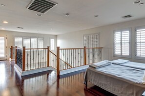A hotel room with a wooden staircase, a bed, and large windows with blinds. - Swim-Up Bar & Games! Ultimate Goodyear Group Stay (Goodyear)