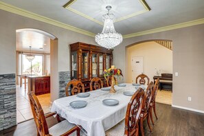 A dining room with a large table set for six, wooden chairs, a chandelier, and a stone accent wall.