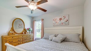 A bedroom with a bed, dresser, mirror, ceiling fan, and a painting on the wall. - Dunnellon Escape w/ Yard: 8 Mi to Rainbow River (Dunnellon)