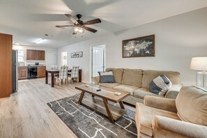 A living room with a wooden coffee table, a sofa, and a dining area with chairs.