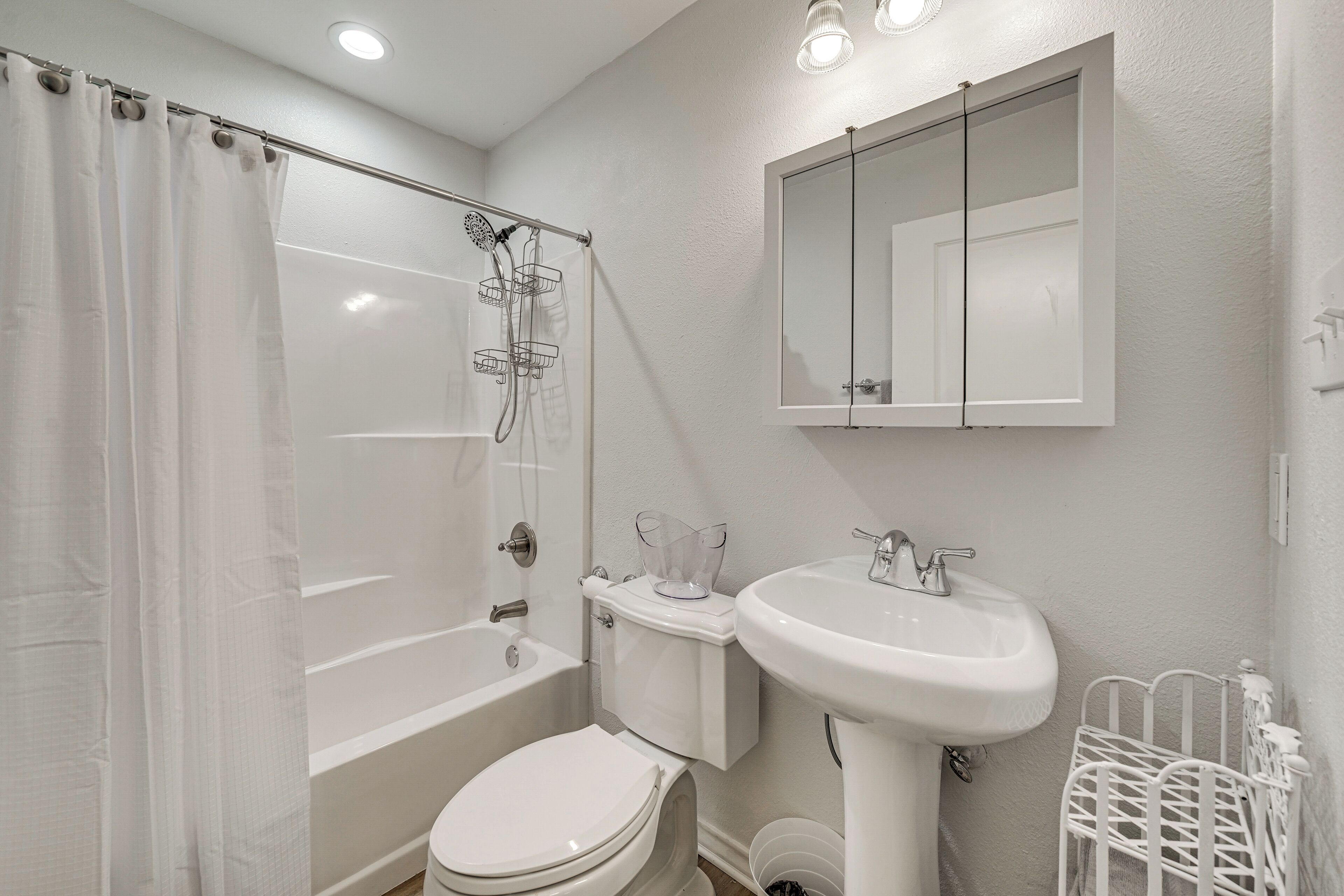 A bathroom with a bathtub, toilet, sink, and a mirror.