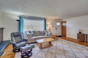 A living room with a sofa, armchair, coffee table, and a rug.