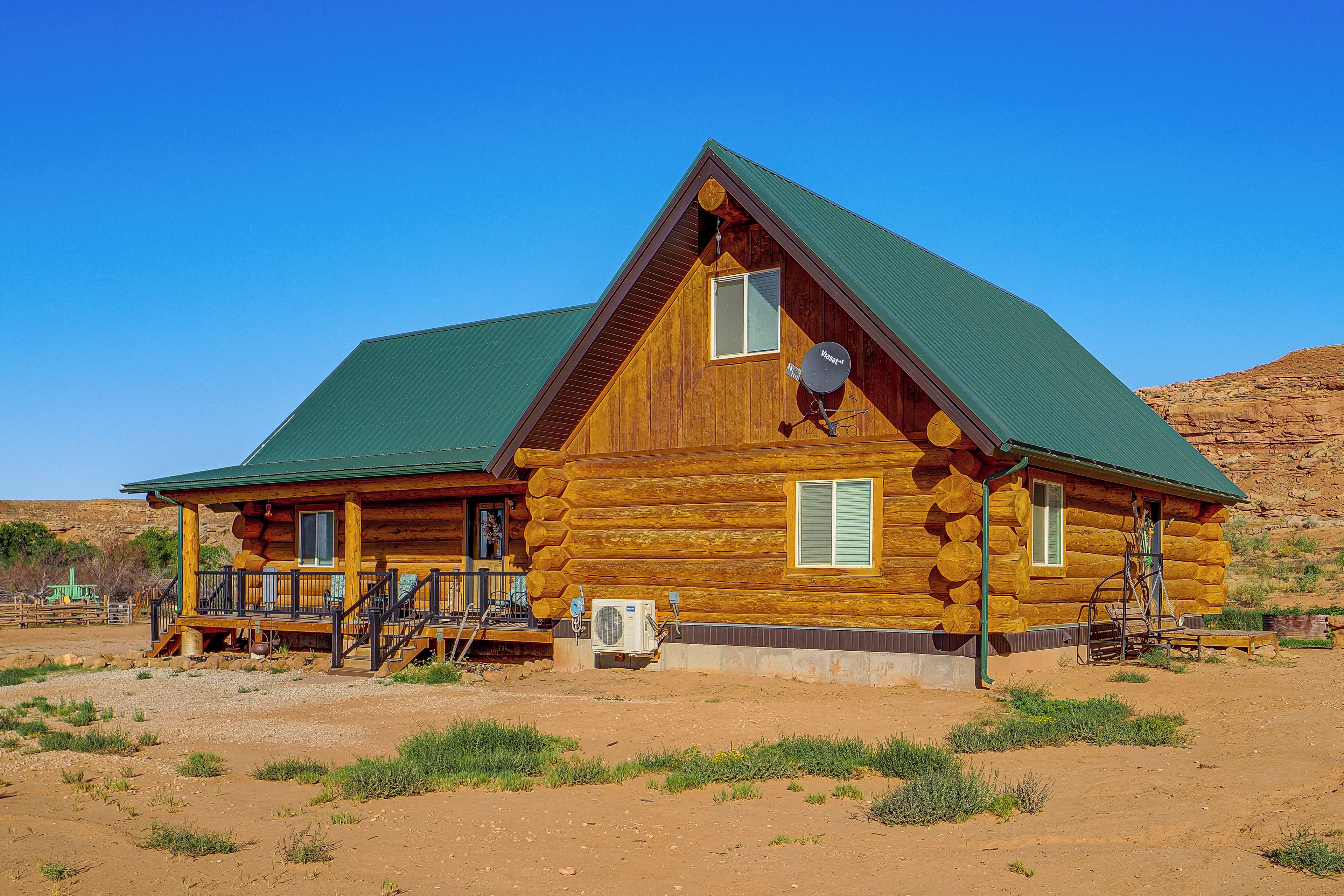 A log cabin with a porch, a satellite dish, and an air conditioning unit.
