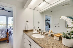 A modern bathroom with a large mirror, white sink, and a ceiling fan. - Sunsets & Sails! Waterfront Punta Gorda Condo (Punta Gorda)
