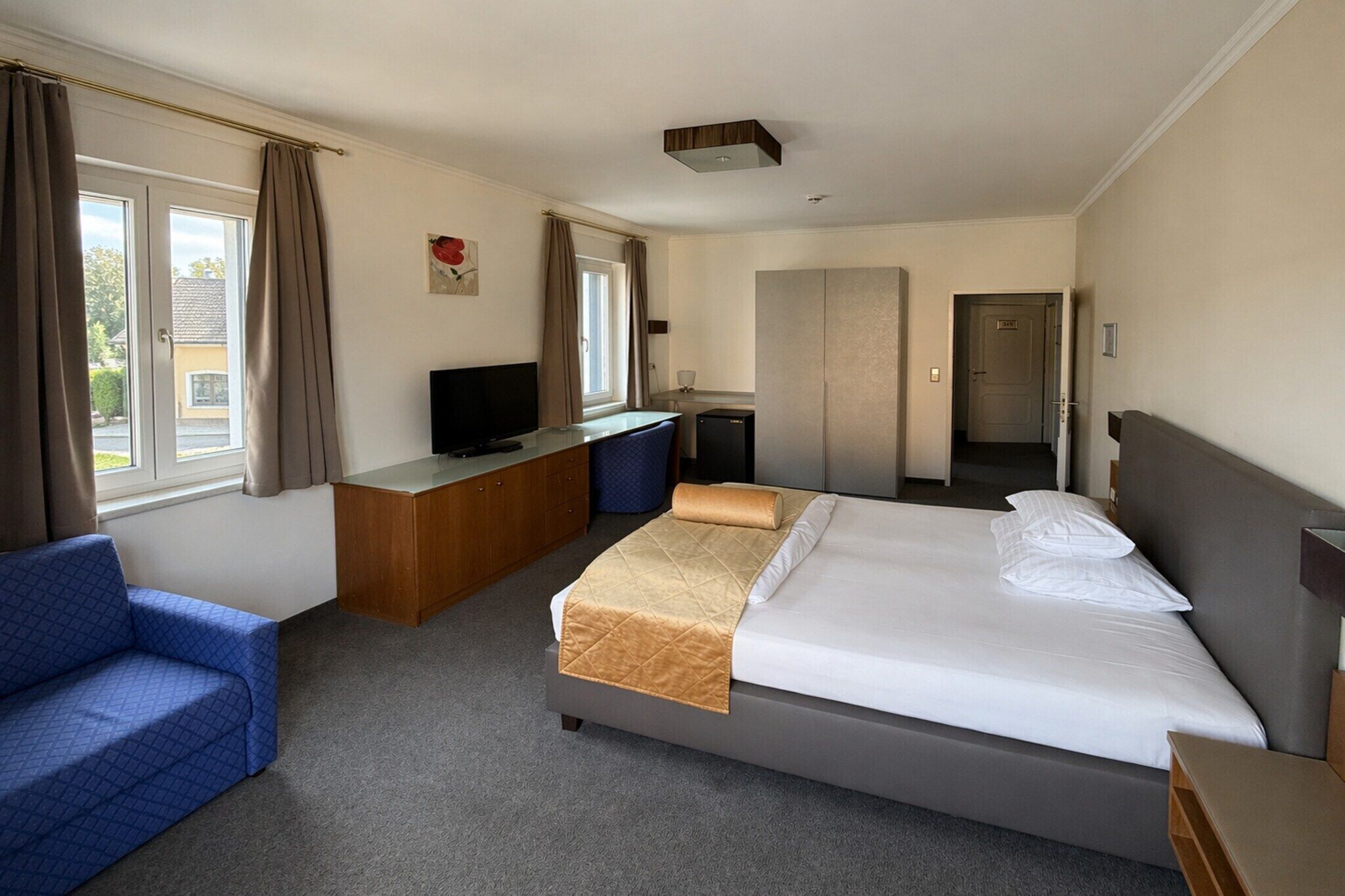 Une chambre d’hôtel équipée d’un lit, d’un bureau, d’une télévision, d’un canapé et offrant une vue sur l’extérieur.