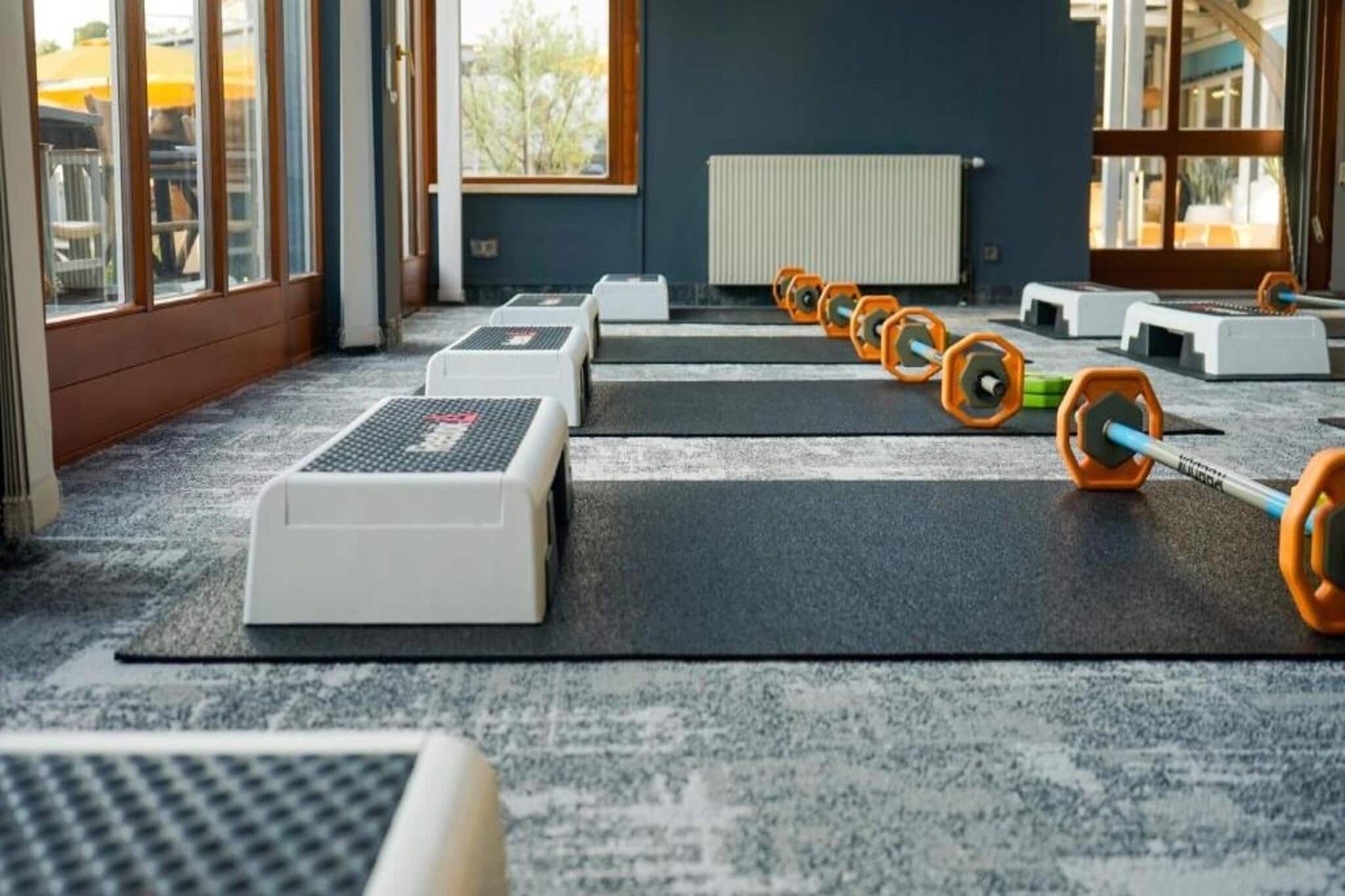 Une salle de sport équipée de matériel de musculation, avec un radiateur et de grandes fenêtres.