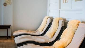 A room with three reclining massage chairs, a small table, and a wall with decorative items.