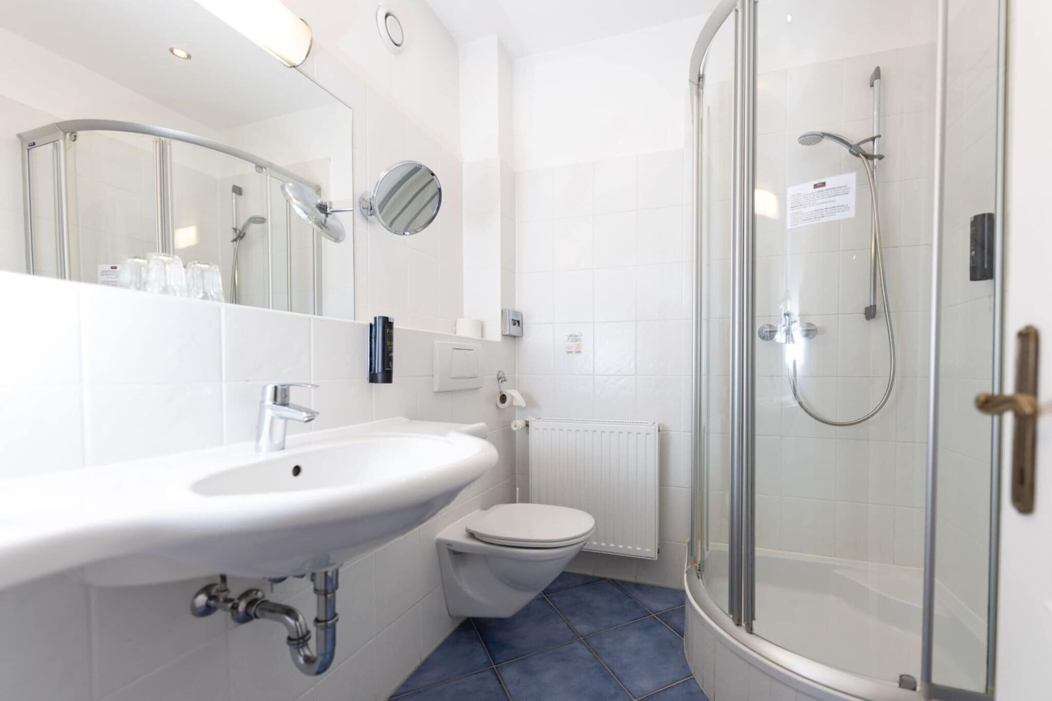 Une salle de bain moderne avec une douche à parois de verre, un lavabo blanc et des toilettes.