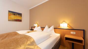 Een hotelkamer met een bed, nachtlampjes, een schilderij aan de muur en een klein houten nachtkastje.