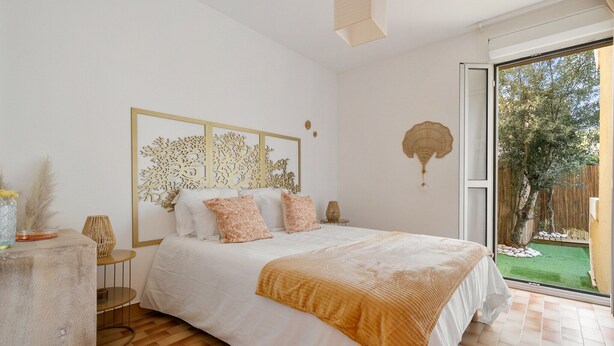 Une chambre à coucher comprenant un lit, une table de chevet, une œuvre d’art murale et une vue sur l’extérieur.