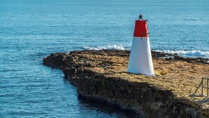 Un phare situé sur un promontoire rocheux, avec la mer en arrière-plan.
