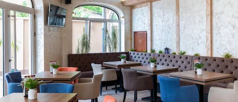 A restaurant interior with high ceilings, large windows, and a mix of seating options including booths and tables.