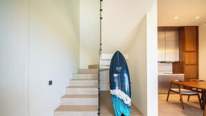 A staircase leading to a dining area with a surfboard leaning against the wall. - Surfside Appartments & Villas (Pecatu)