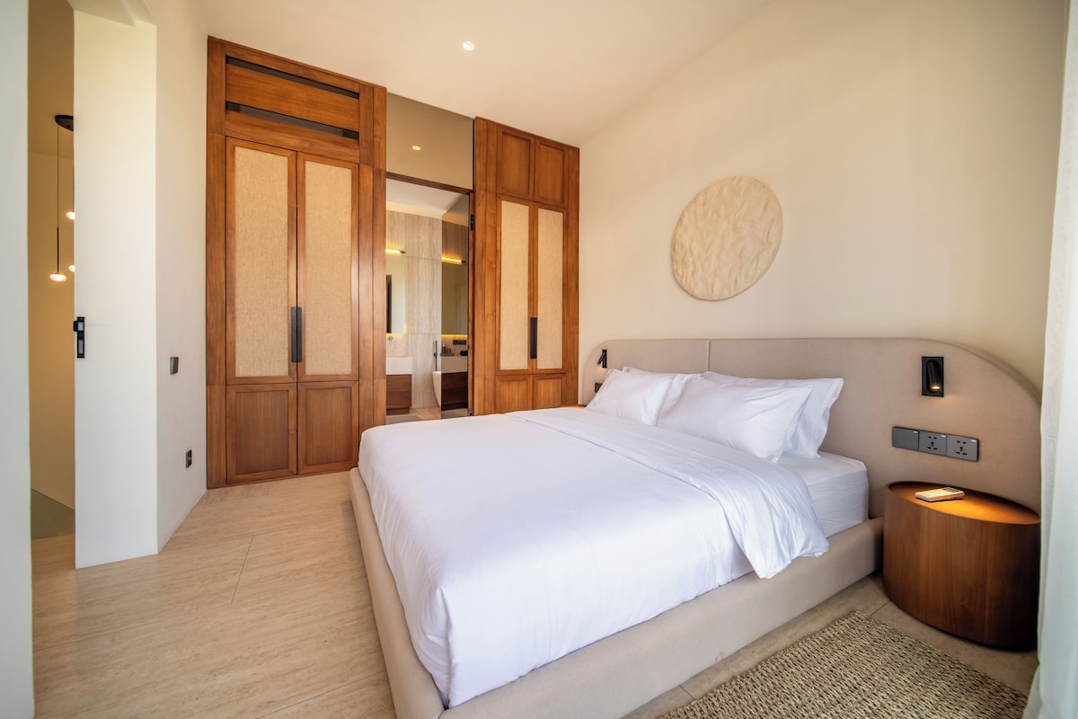 A bedroom with a large bed, wooden wardrobe, and a round wall decoration.
