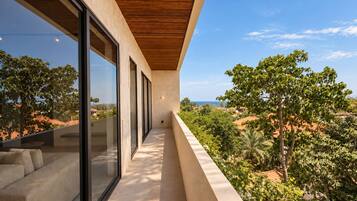 A modern balcony with a view of a lush landscape and distant buildings.