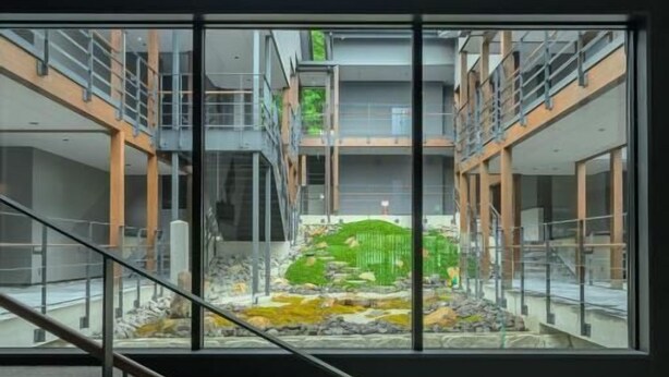 Moderni rakennus, jossa on lasikattoinen sisäpiha, portaikko ja näkymä ulkoilma-sisäpihalle.