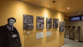 A hallway with a large black and white photograph of a person, several smaller black and white photographs on the wall, and informational plaques.