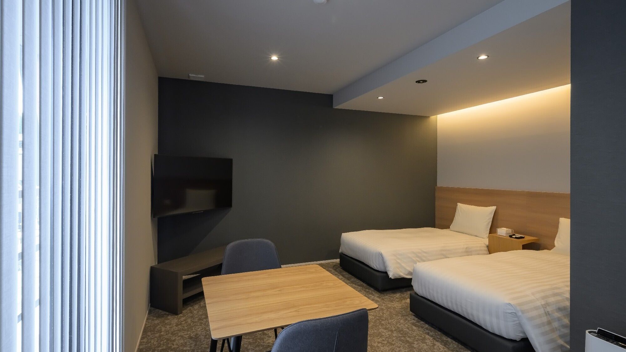 A hotel room with two beds, a TV, a desk, and a chair.