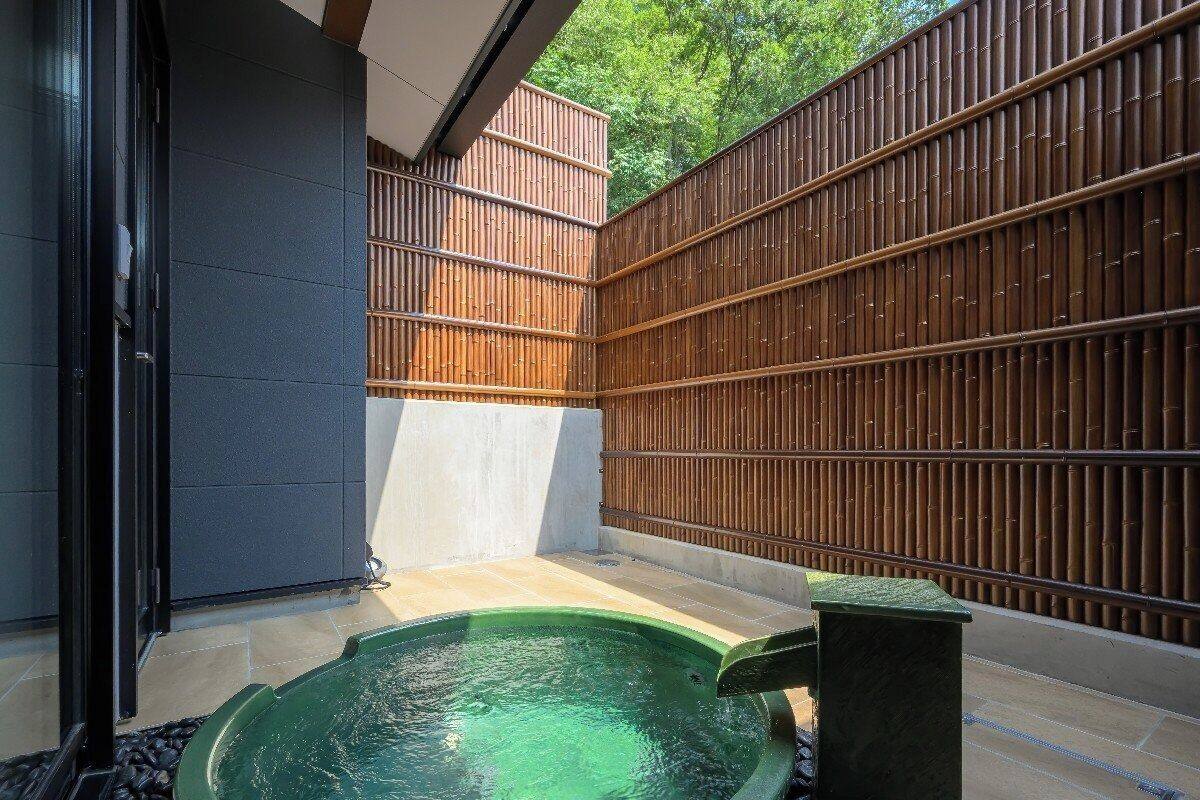 Ein Wellnessbereich mit Whirlpool, Steinboden und Bambusumzäunung.