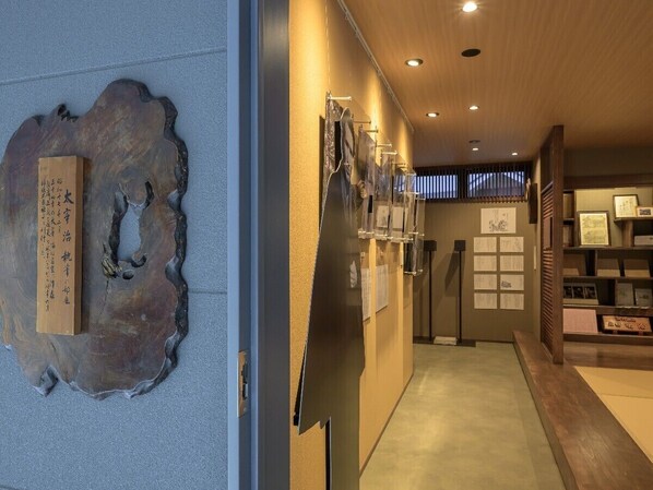 Een hal met een houten wand, een groot abstracte sculptuur en ingelijste documenten aan de muur.