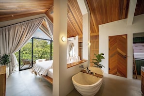 Un dormitorio moderno con un ventanal grande, techo de madera, cama y vista a la vegetación.