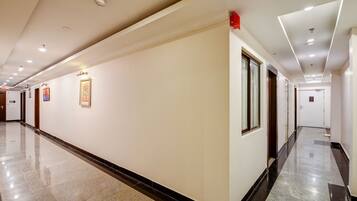 A long, well-lit hallway with a polished floor, framed artwork on the walls, and a door at the end.