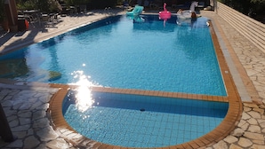 Une piscine bordée de pierres, des chaises longues et un mur en pierre.