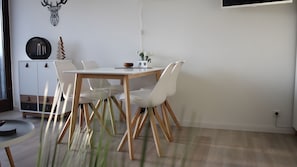 A modern dining area with a white table and chairs, a cabinet with drawers, and a mounted deer head decoration.