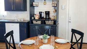 A dining area with a round table set for four, dark blue cabinetry, and a pendant light above.
