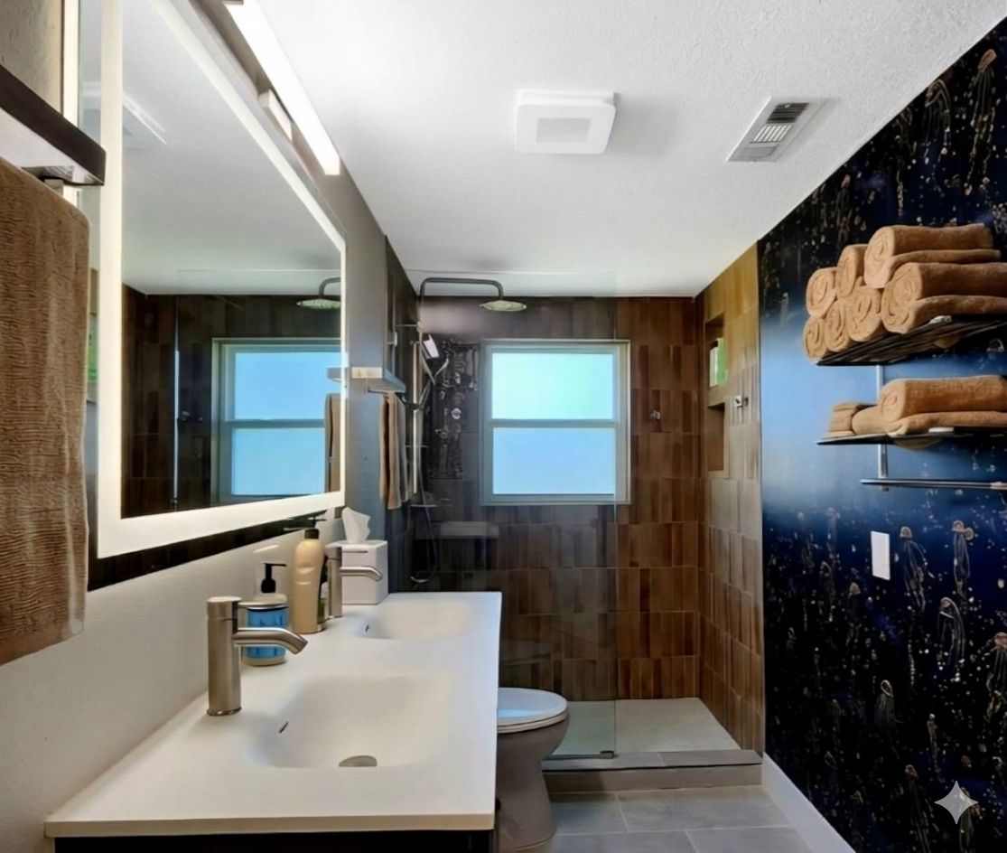 Un baño moderno con un espejo grande, un lavabo, un inodoro y una ducha.
