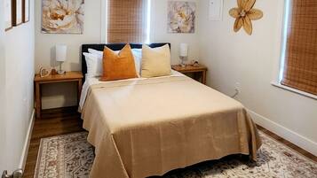 A bedroom with a bed, nightstands, a ceiling fan, and a patterned rug.