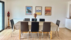 Een eetruimte met een tafel gedekt voor zes personen, omringd door stoelen, met drie ingelijste posters aan de muur.