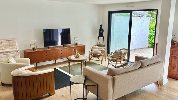 Een moderne woonkamer met een bank, stoelen, een televisie en een houten kast.