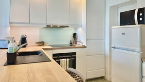 Een moderne keuken met witte kasten, een ingebouwde oven, een magnetron en een koelkast.