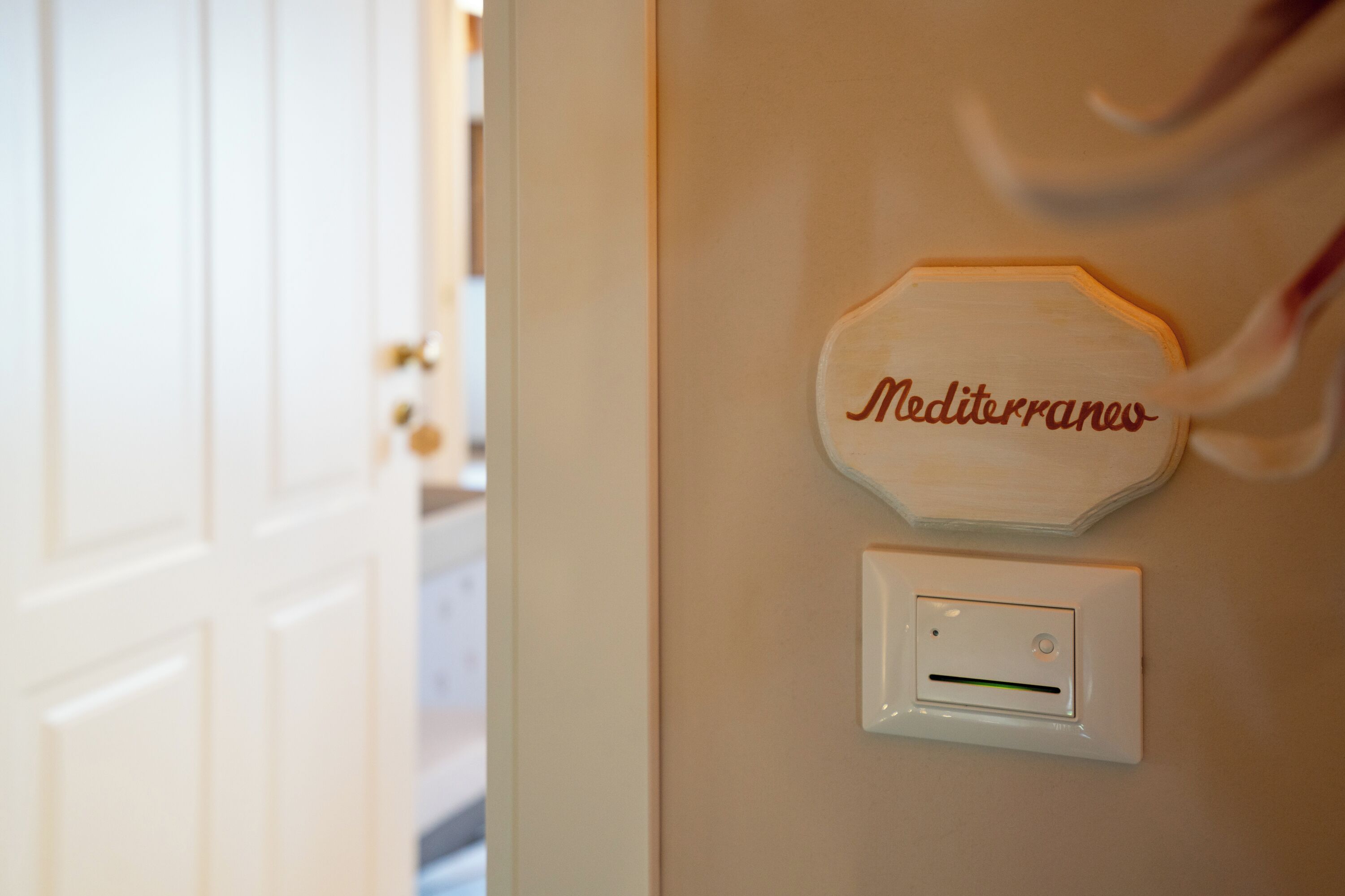A wall-mounted sign with 'Mediterraneo' and a light switch.