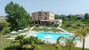 Un hôtel doté d’une piscine, de chaises longues et de palmiers.