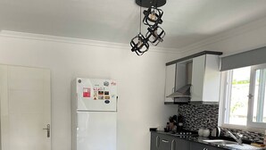 A modern kitchen with a wooden dining table, a refrigerator, and a window. - Sylvana Apartment- a Little Piece of Kalkan Heaven (Kaş)