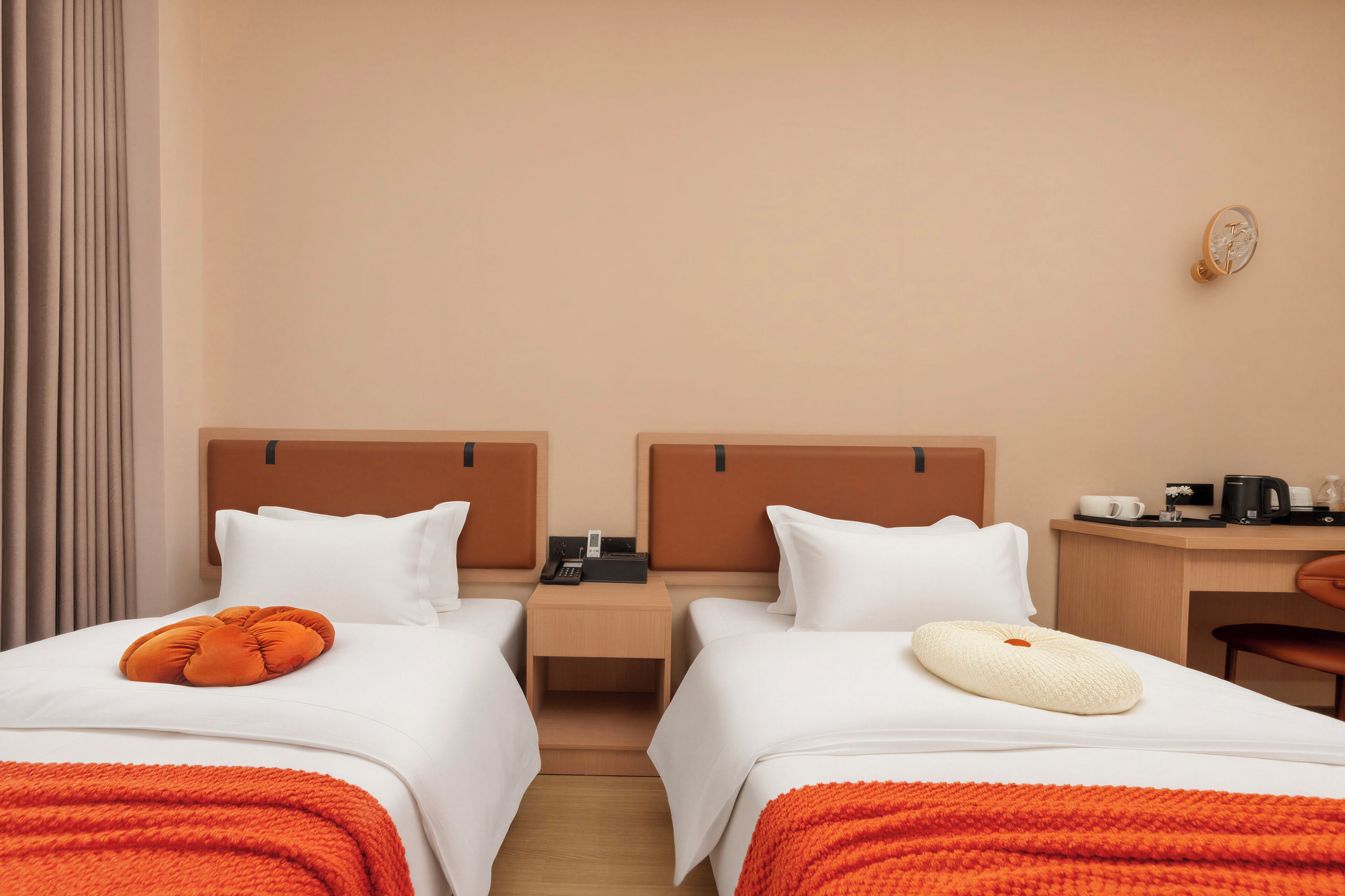 A hotel room with two beds, a desk, a chair, and a nightstand with a phone.