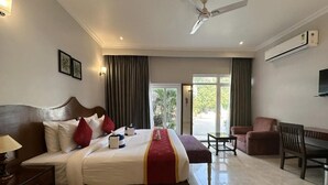 Camera d'albergo con un letto grande, una scrivania, una sedia, una ventola a soffitto e un condizionatore d'aria.