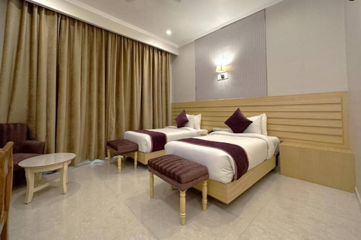 Une chambre d’hôtel avec deux lits, une petite table, une chaise et un ventilateur de plafond.