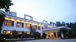 Un hotel moderno con ingresso coperto, ampie finestre e un giardino curato.